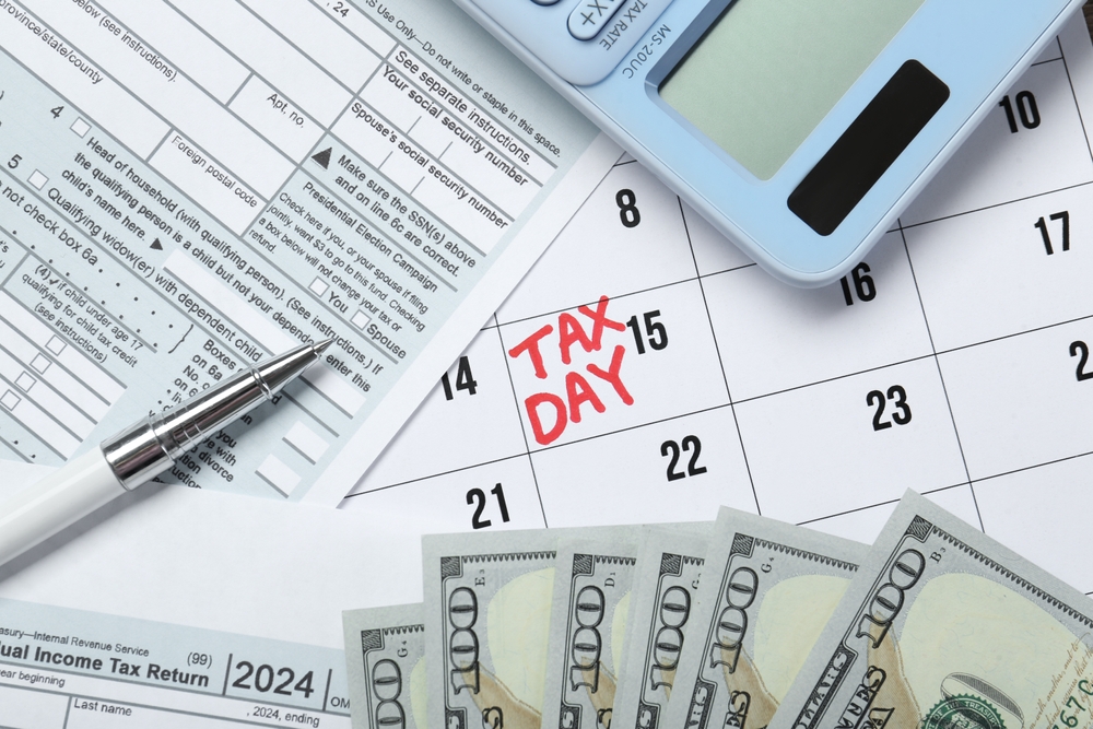 استمارات ضريبية وآلة حاسبة ونقود وتقويم مُحاط فيه «Tax Day» بدائرة