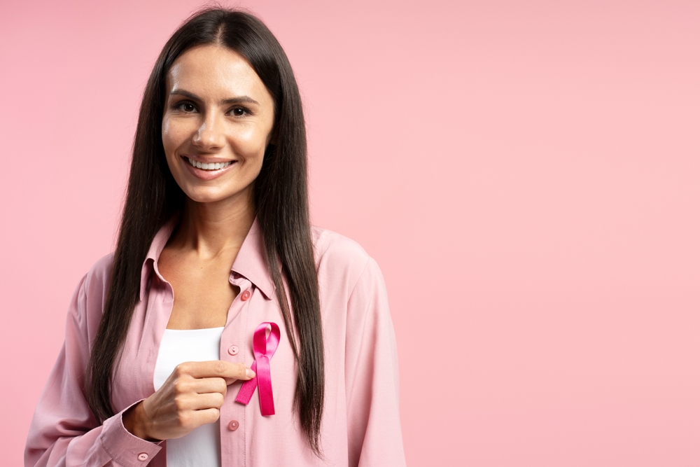 A woman in pink holding a pink awareness ribbon
