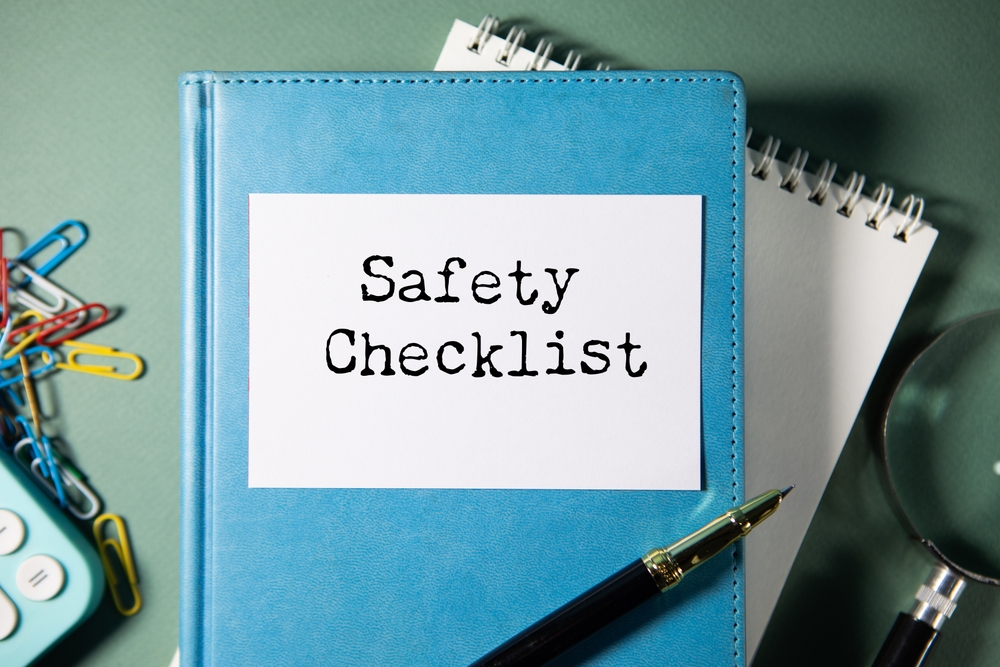 A notebook labeled Safety Checklist with a pen, paper clips and a magnifier