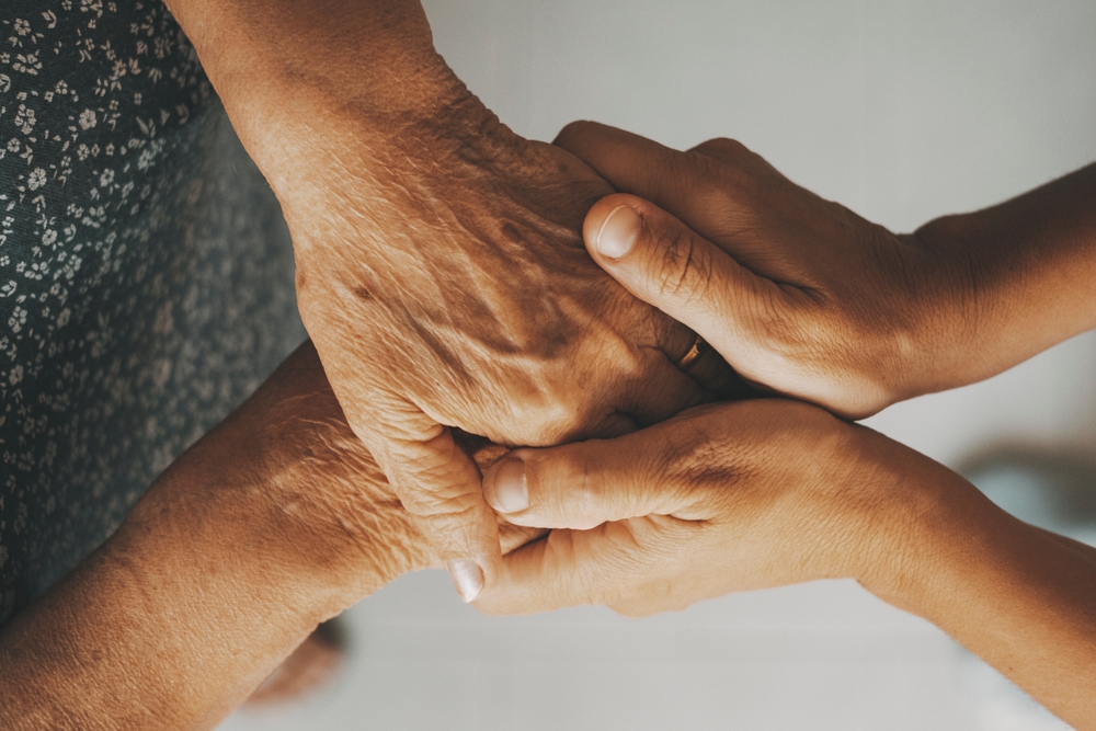 Unas manos jóvenes sosteniendo con delicadeza las manos de una persona anciana