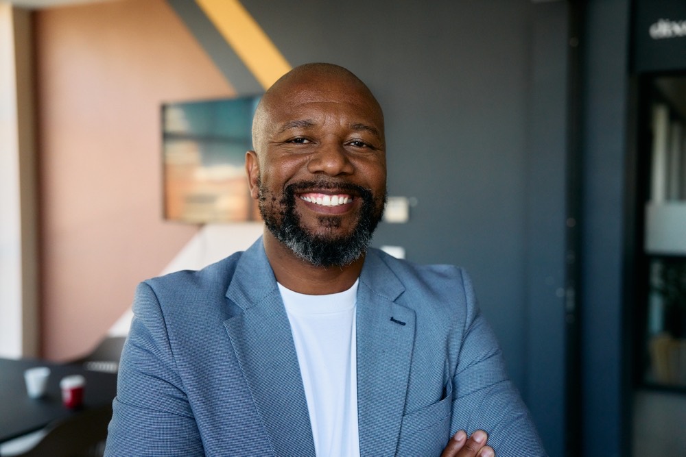 A smiling man in a blazer at his office