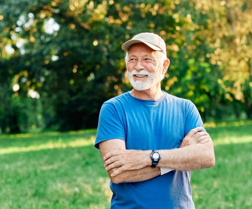 An older man in a cap smiling outdoors