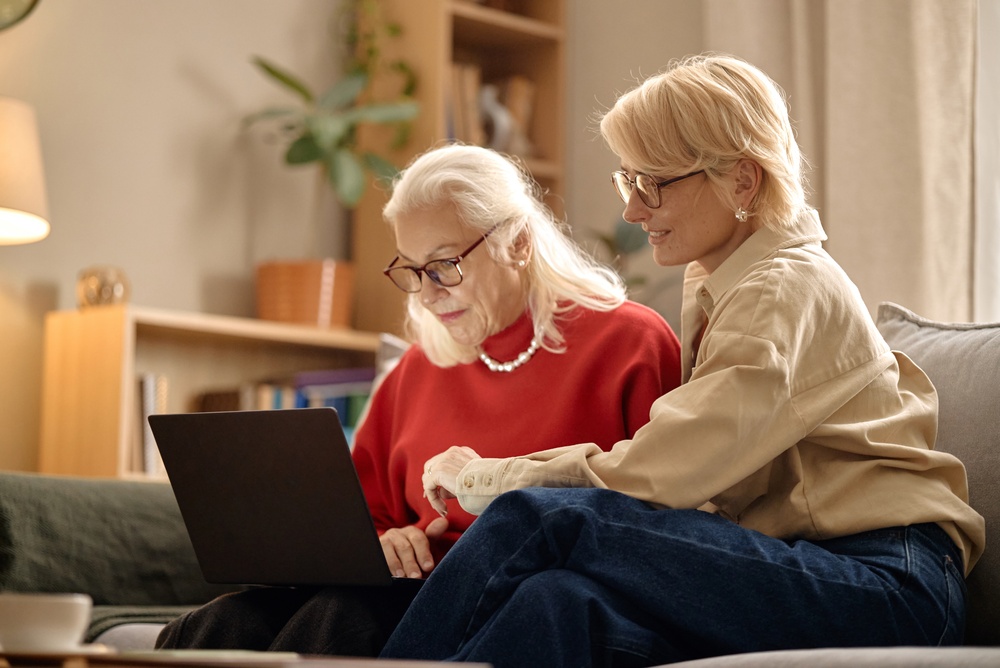 A daughter helping her elderly mother with paperwork on a laptop