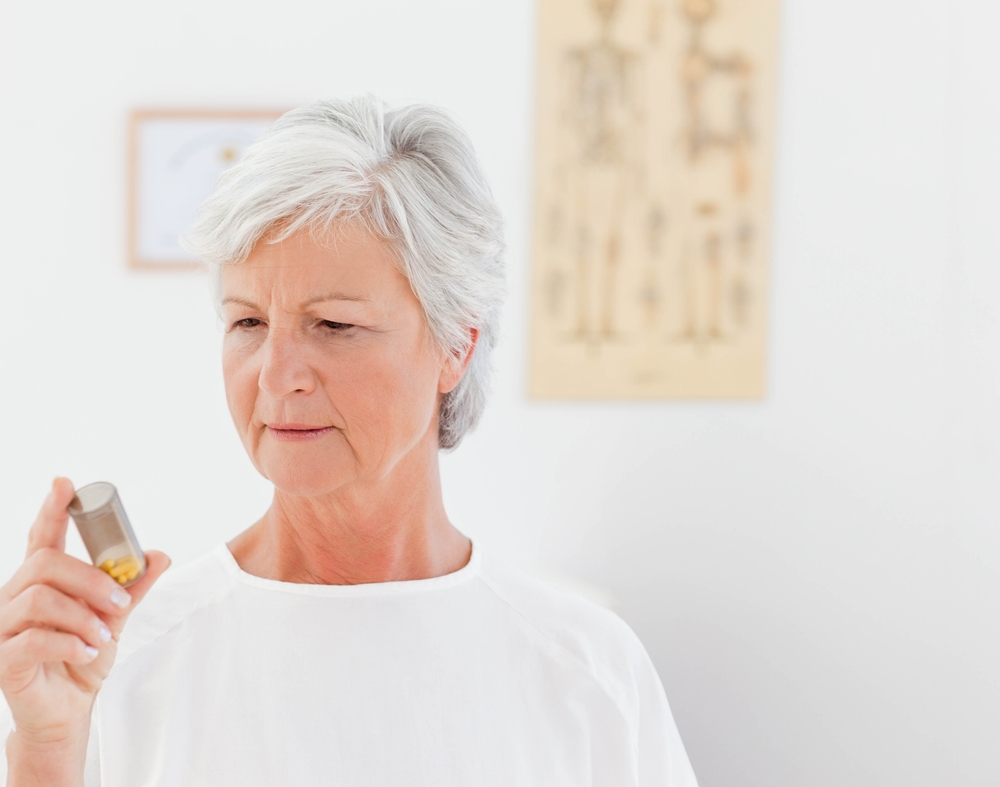 An older woman reading the label on a pill bottle