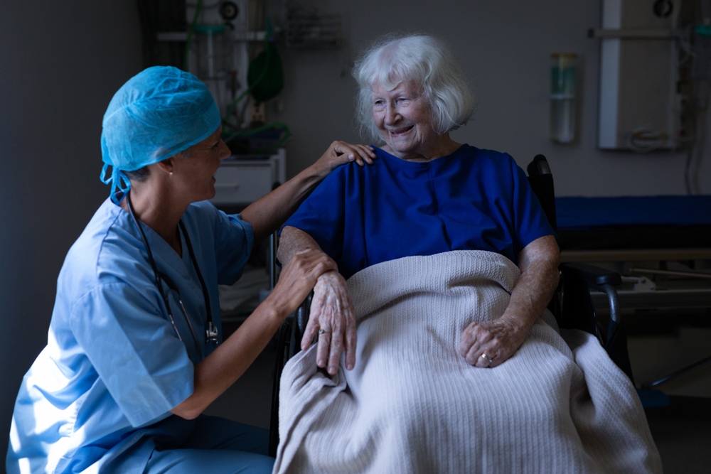 A surgeon in scrubs reassuring an older woman before surgery