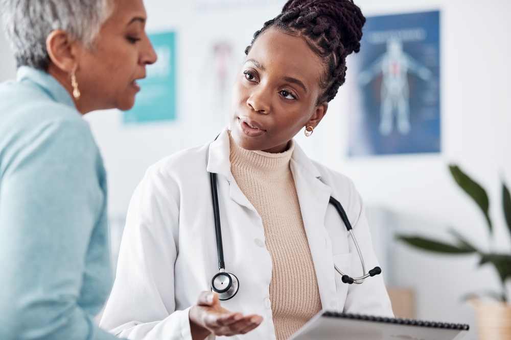 A doctor explaining a diagnosis to an older woman in an exam room