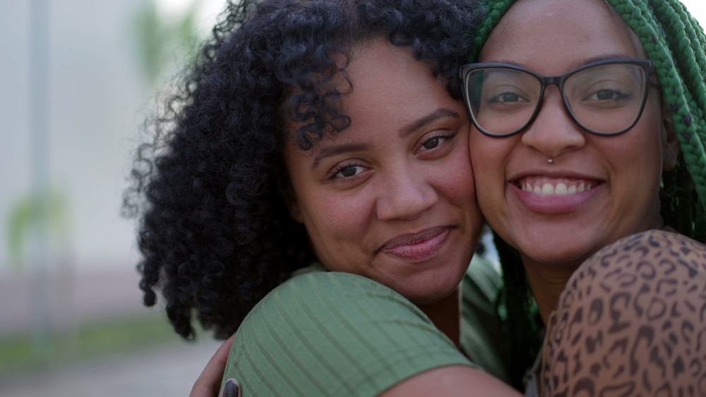 Two sisters smiling with their heads together