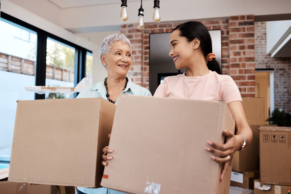 An older woman and her daughter carrying moving boxes into a home