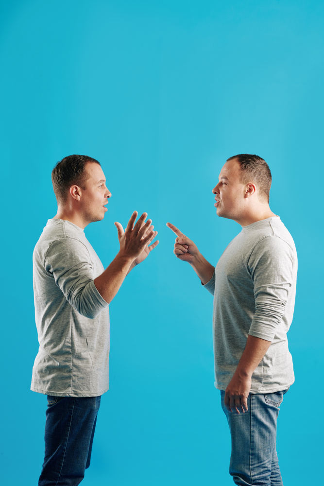 Two brothers arguing face to face against a blue background